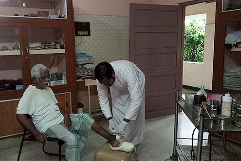 Das Bild zeigt die Versorung eines Kranken in Indien durch einen Barmherzigen Brüder