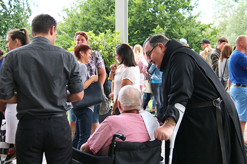 Das Bild zeigt Novizenmeister Frater Richard Binder im Gespräch mit einem Bewohner im Rollstuhl.