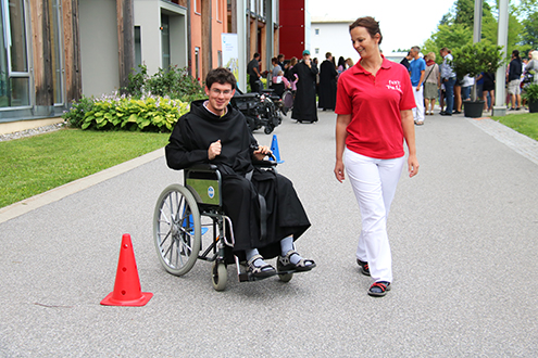 Das Bild zeigt einen Novizen der Barmherzigen Brüder beim Ausprobieren des Rollstuhlparcours. 