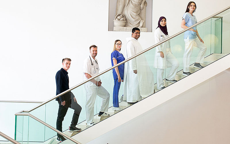 Das Bild zeigt Mitarbeiterinnen und Mitarbeiter auf einer Treppe. / Barmherzige Brüder / Wolfstudios