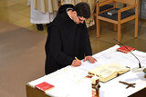 Frater Sebastian unterschriebt die Professurkunde am Altar.