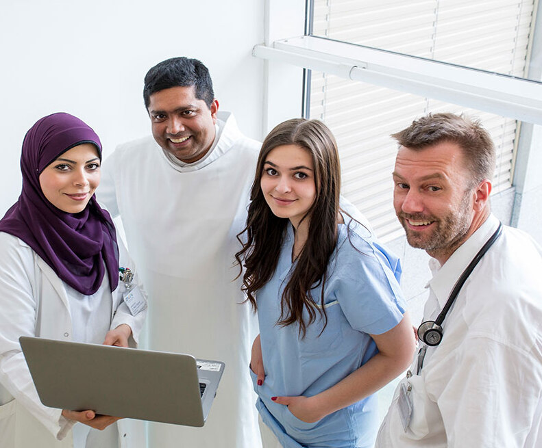 Teambild / Barmherzige Brüder Mitarbeitende aus Pflege und Medizin der Barmherzigen Brüder: Eine Pflegeperson mit Kopftuch, ein Barmherziger Bruder im weißen Habit, eine Pflegeperson und ein Arzt.