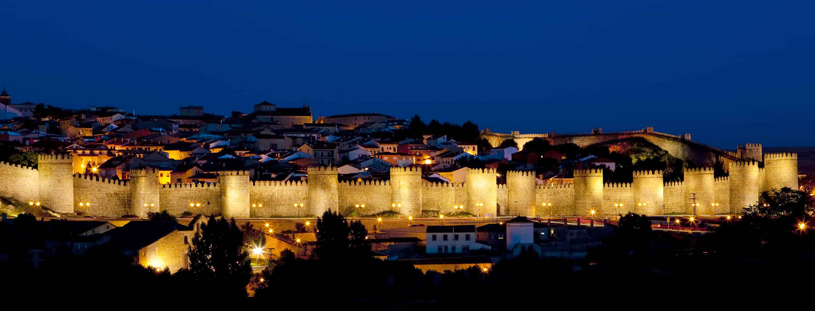 Das Bild zeigt eine Ansicht der Stadt Ávila in der Nacht.