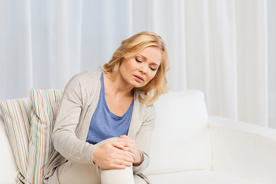 Eine Frau sitzt auf einer Couch und hält ihr Knie.